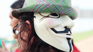 PSP Anaheim Anonme Kit O'Connell wearing an Anonymous mask on the back of his head, under a green hat.