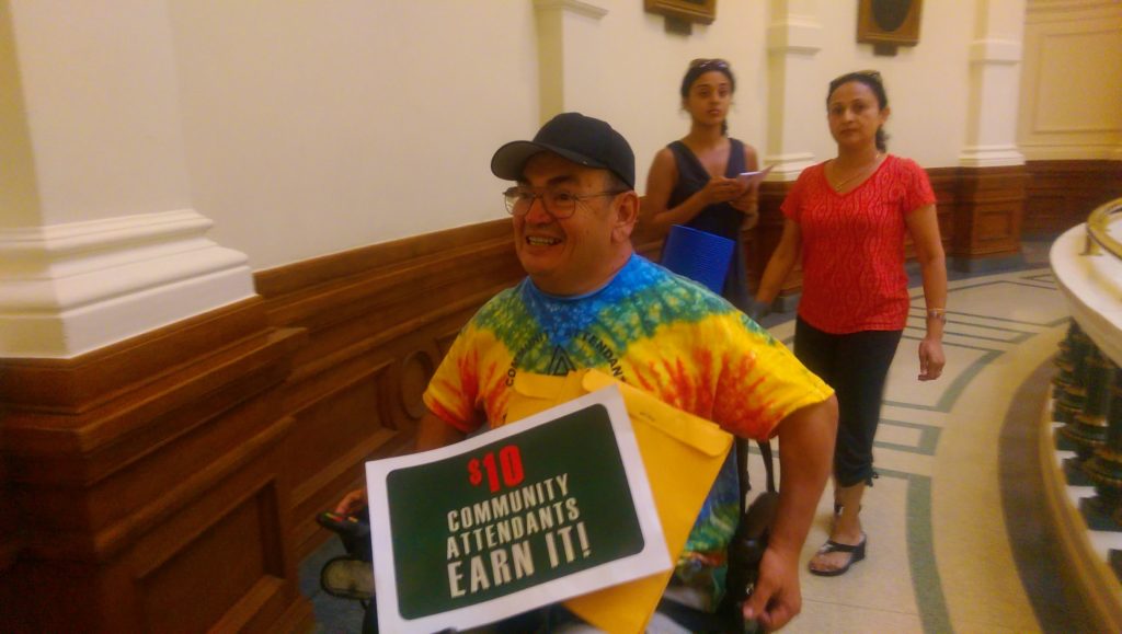 In this May 15, 2015 photograph, Danny Saenz holds a sign demanding $10/hour wages for personal care attendants, along with other protesters at the Texas Capitol. (Kit O'Connell)